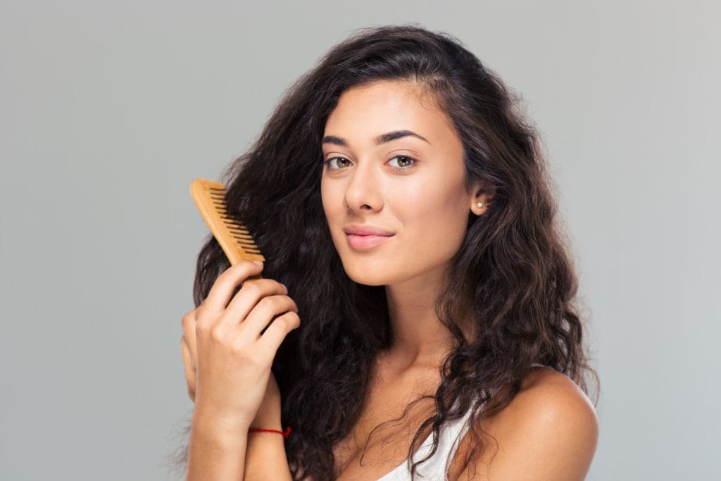 Let’s Talk Postpartum Hair Loss! 1 happy cute woman combing her hair SBI 300968019 1