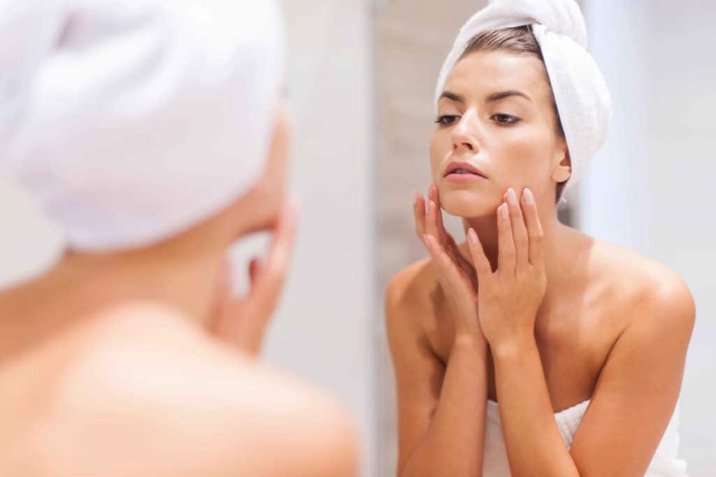 Investing in your skin! 3 woman looking on reflection in the mirror after shower SBI 328444976 11zon