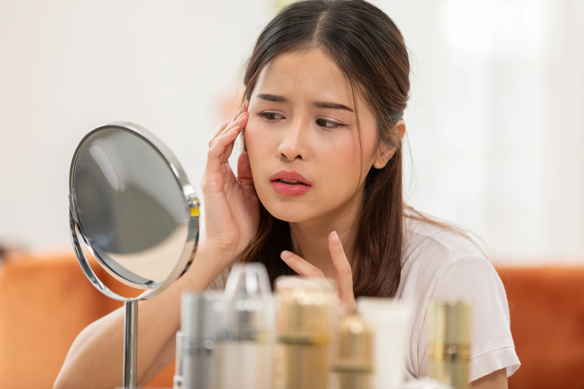 Blog 2 Woman examining her face in a mirror | Gretchen W Frieling MD